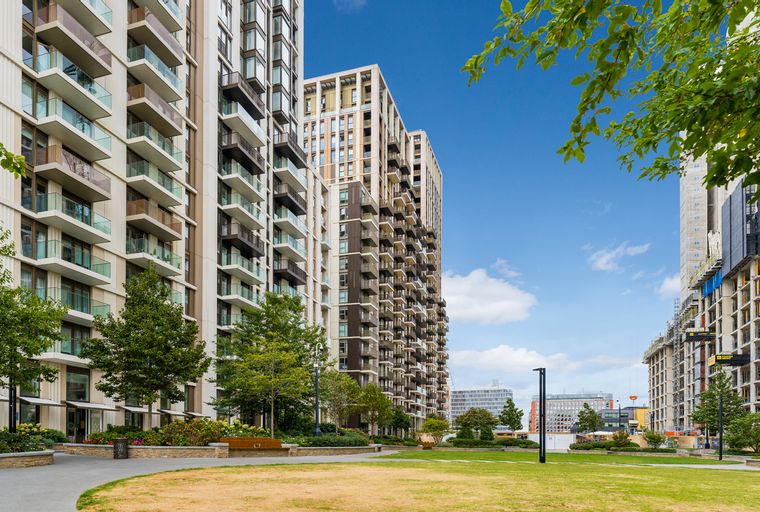 A view of modern apartment buildings with balconies and a park in front.