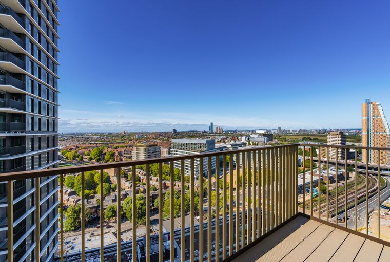 A balcony overlooking a city skyline with buildings and trees.