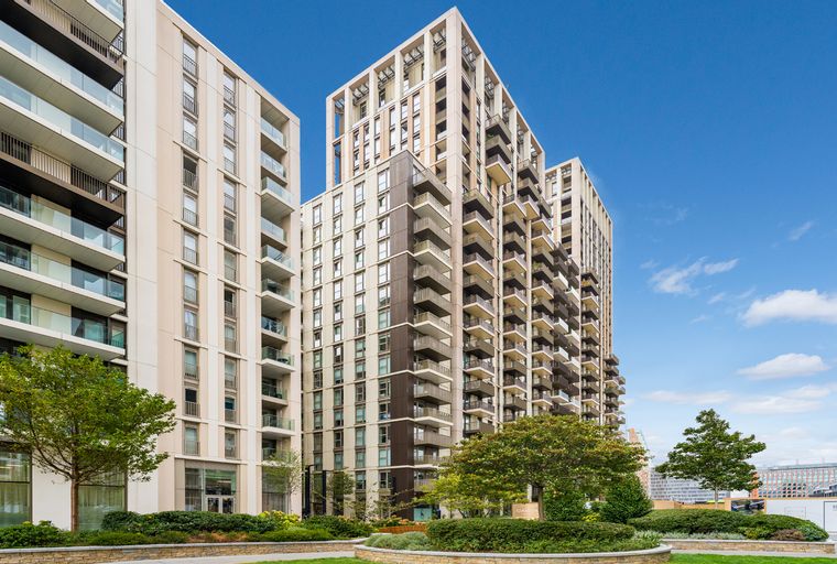 A view of modern apartment buildings with balconies and trees in the foreground.