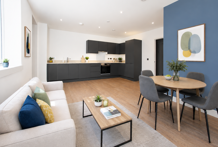 A living and kitchen area with a sofa, coffee table, dining table, and kitchen cabinets.