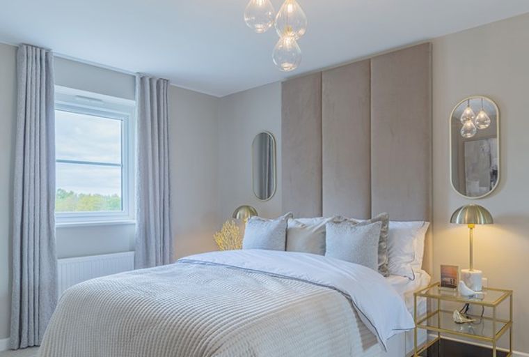 A bedroom with a bed, headboard, window, curtains, and a bedside table.