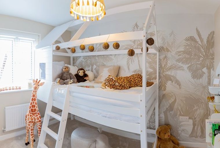 A children's bedroom with a loft bed, stuffed animals, and jungle-themed wallpaper.