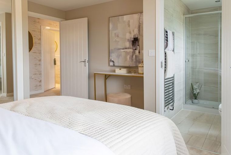 A bedroom with a bed, a dressing table, and an en-suite shower room.