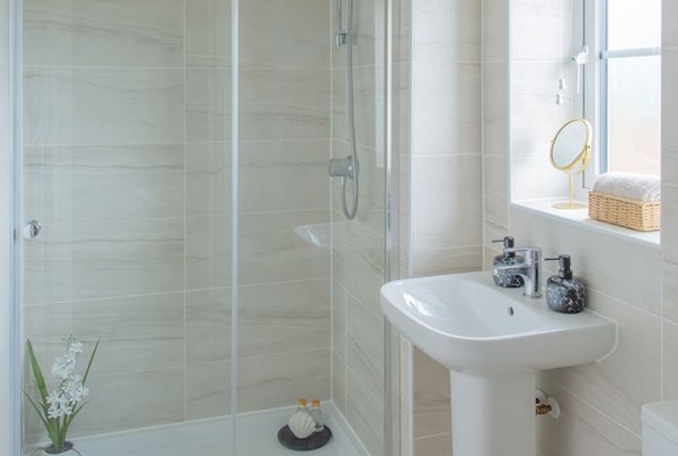 A bathroom with a shower, sink, and window.