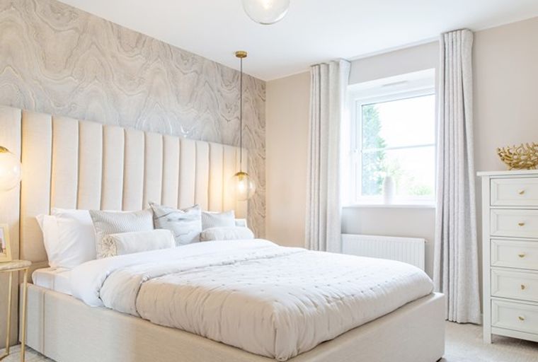 A bedroom with a bed, headboard, wallpaper, window, and dresser.