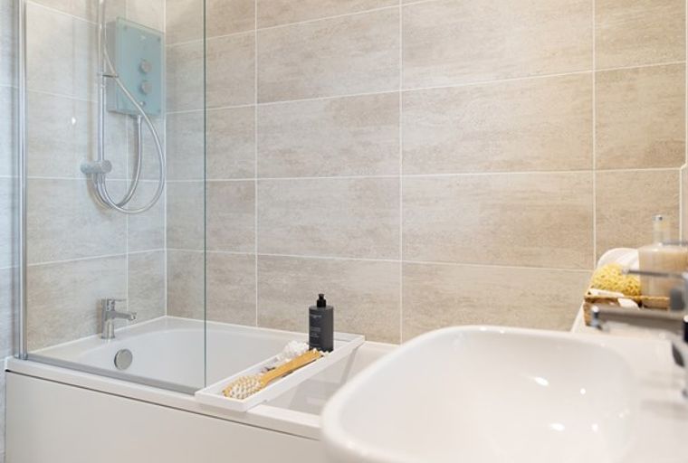 A bathroom with a bathtub, shower, and sink.