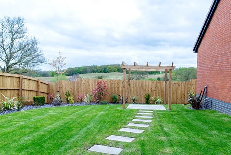 A backyard with a wooden pergola, a stepping stone path, and a green lawn.