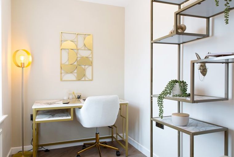 A home office with a desk, chair, and shelving unit.