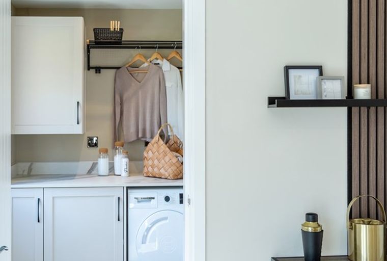 A laundry room with a washing machine, cabinets, and a hanging rack.
