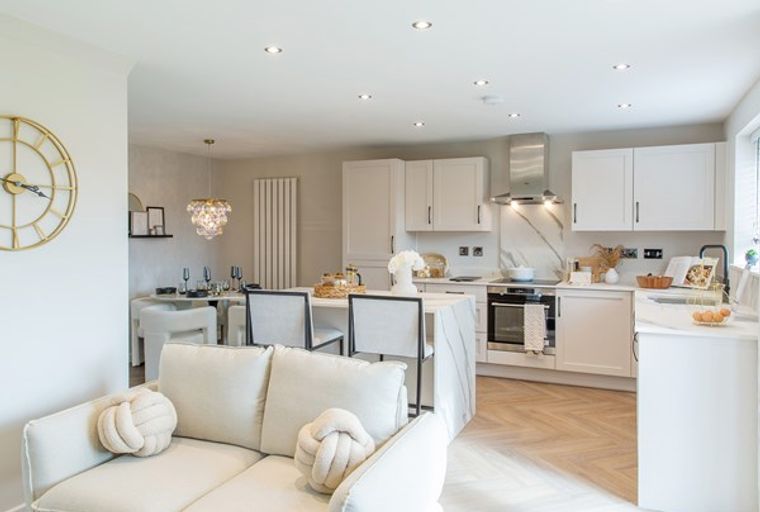 A modern open-plan living, dining, and kitchen area with white cabinets, a marble backsplash, and a dining table.