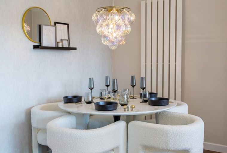 A dining table set with chairs, a chandelier, and wall decor.