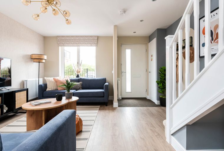 A living room and entryway with a blue sofa, coffee table, and a staircase.