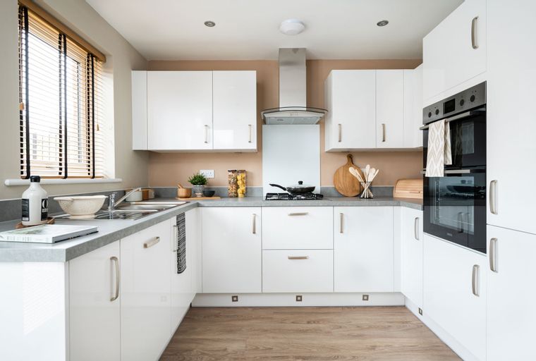 A modern kitchen with white cabinets, a grey countertop, and integrated appliances.