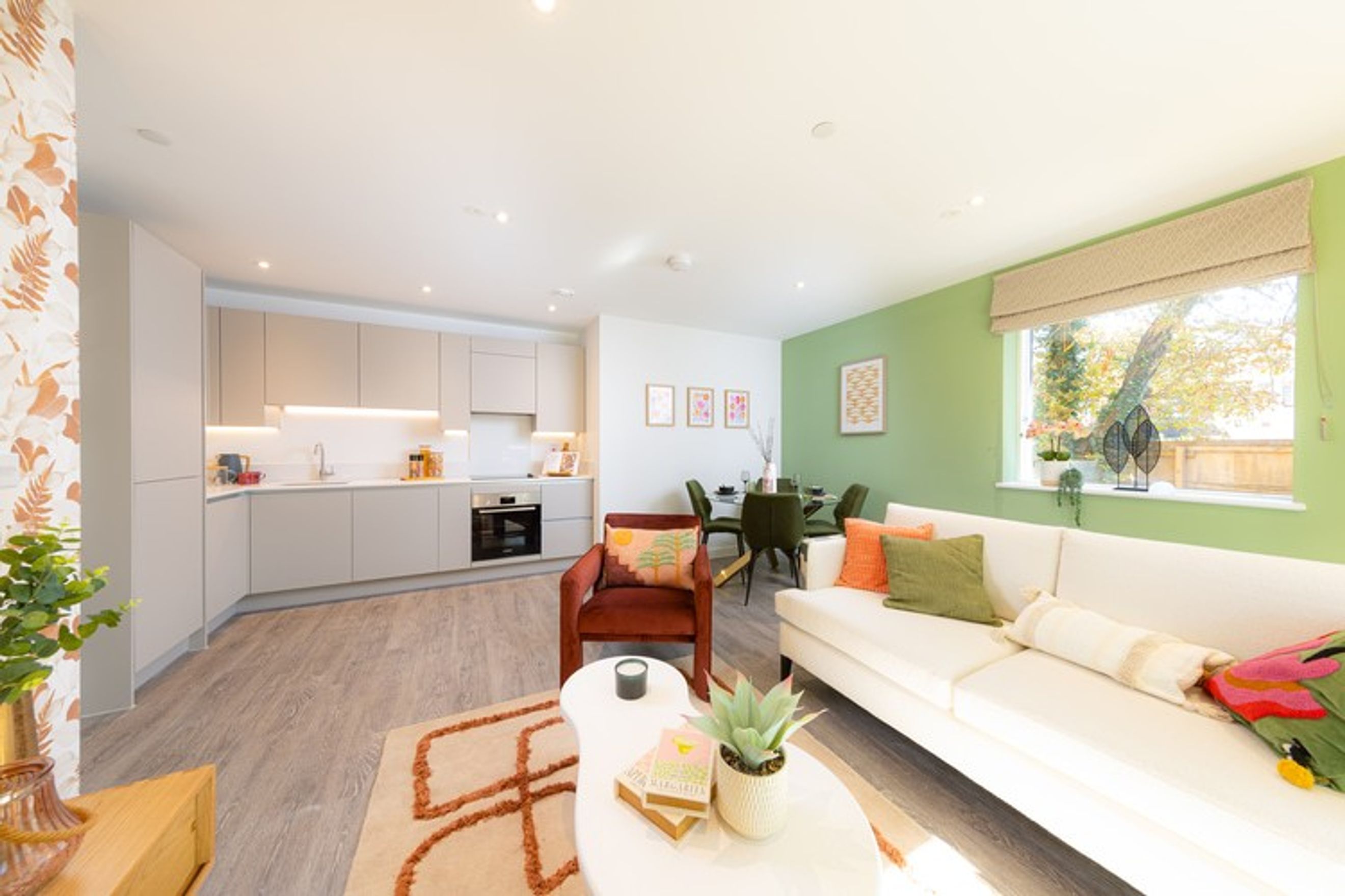 A living room and kitchen area with a sofa, chairs, and a dining table.