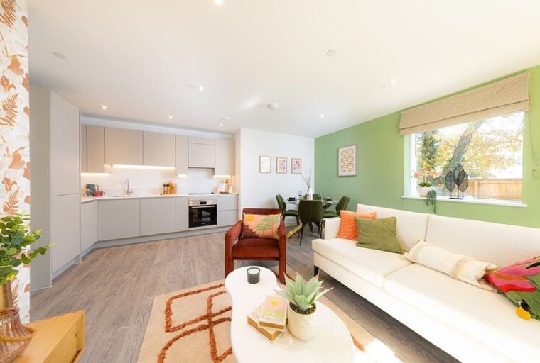 A living room and kitchen area with a sofa, chairs, and a dining table.