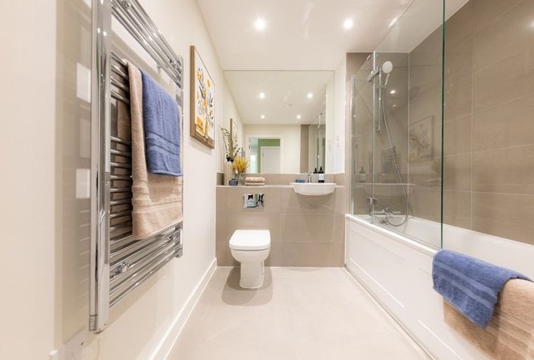 A bathroom with a toilet, sink, bathtub, and a towel warmer.