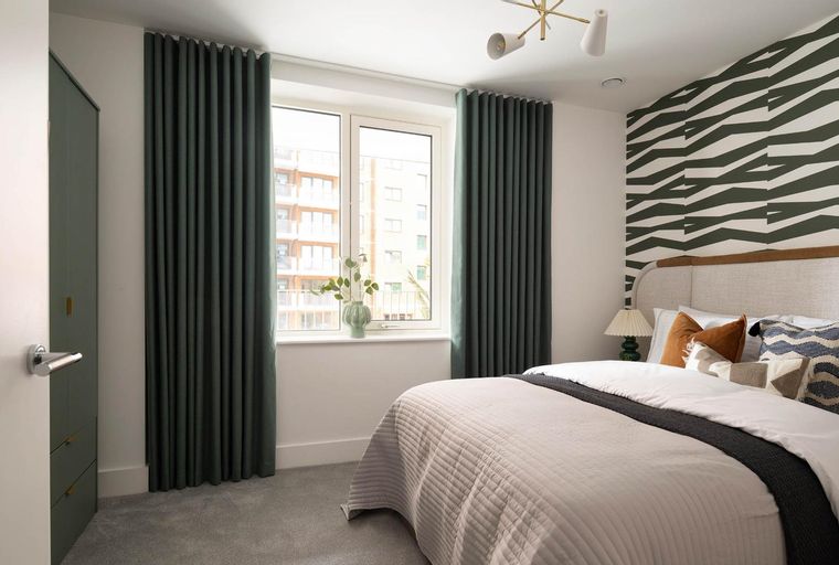 A bedroom with a bed, window, curtains, and a wardrobe.