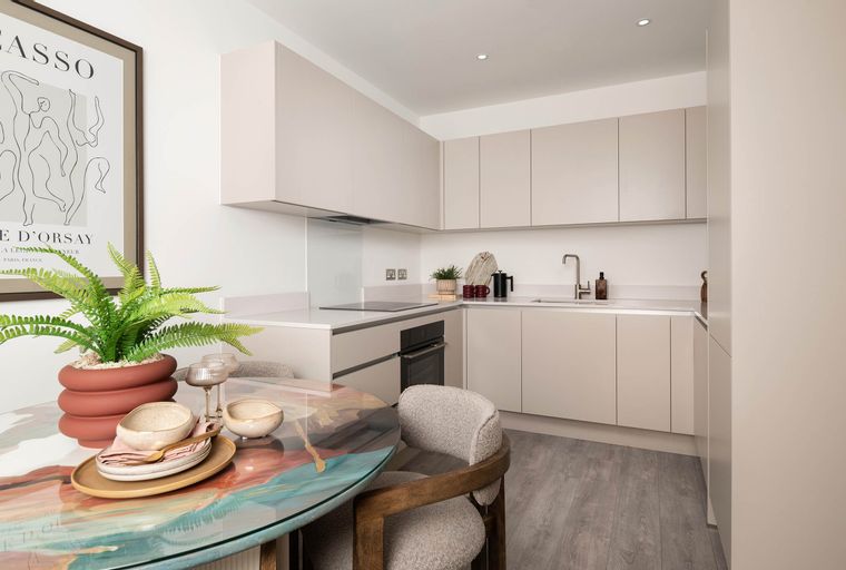 A dining area and kitchen with a round table, chairs, and modern cabinetry.