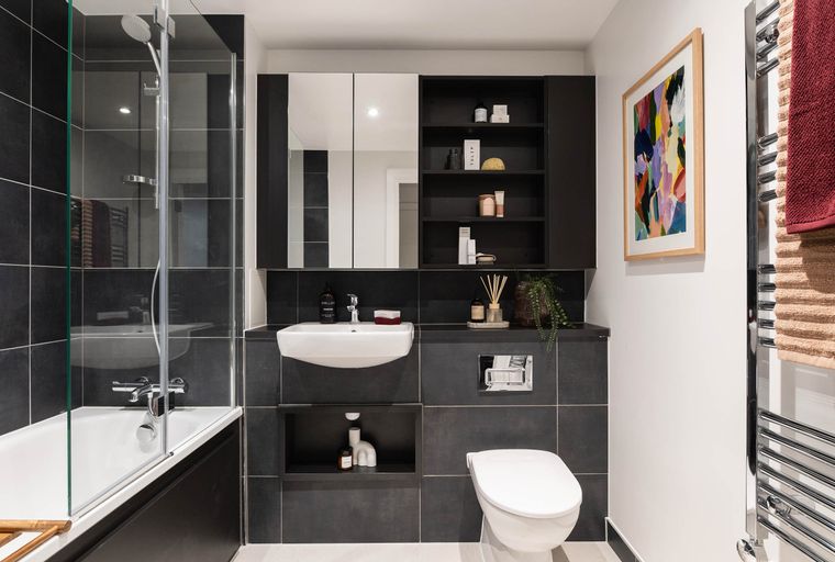 A modern bathroom with a bathtub, sink, toilet, and artwork.