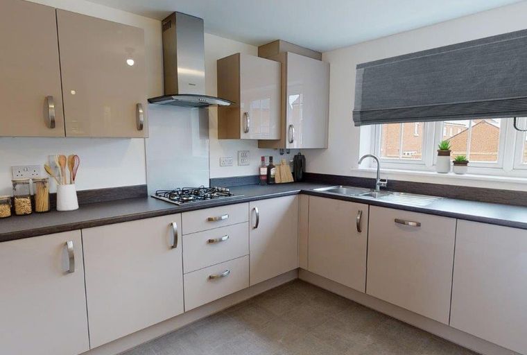 A kitchen with light-colored cabinets, a gas stove, and a sink under a window.