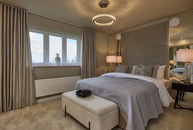 A bedroom with a bed, headboard, bedside lamps, and a chandelier.