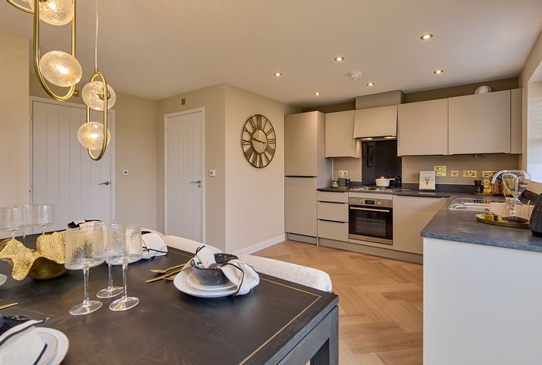 A dining area and kitchen with a table, chairs, pendant lights, and kitchen cabinets.