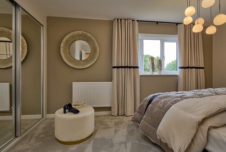A bedroom with a bed, a mirror, and an ottoman.