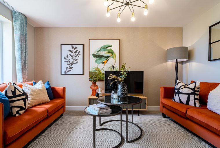 A living room with two orange sofas, a coffee table, and artwork on the wall.