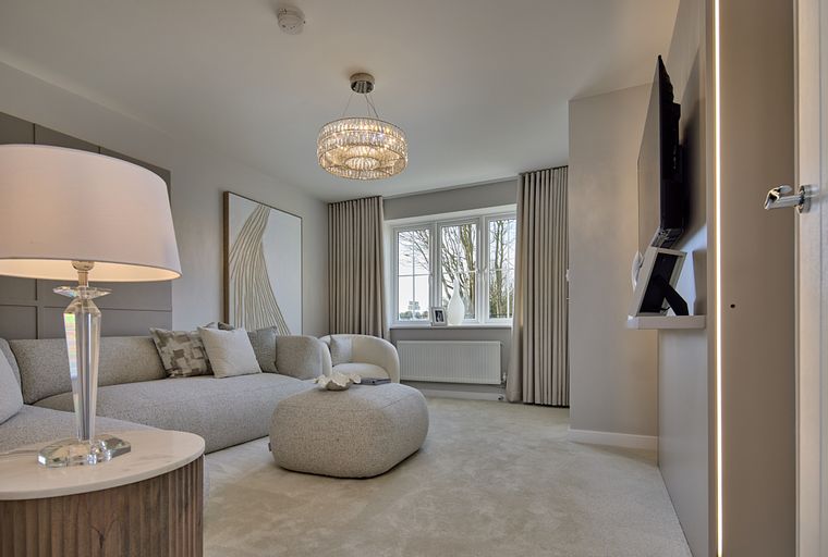 A living room with a sectional sofa, ottoman, chandelier, and a large window.