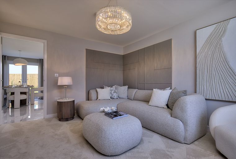 A living room with a sectional sofa, ottoman, and a chandelier.