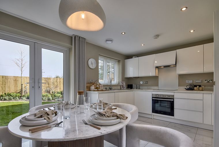 A dining area and kitchen with white cabinets and a marble table.