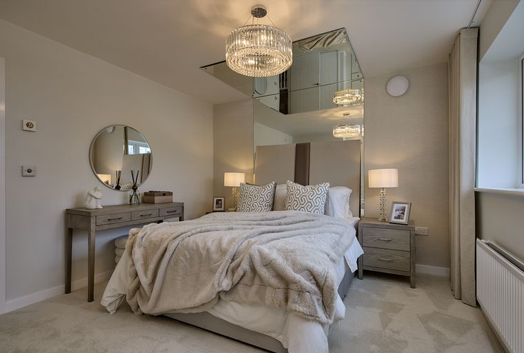 A bedroom with a bed, nightstands, and a vanity table.