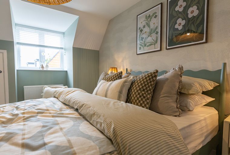 A bedroom with a bed, pillows, and a window.