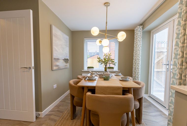 A dining room with a table, chairs, a chandelier, and a painting.
