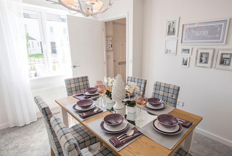 A dining room table set for a meal with chairs around it.