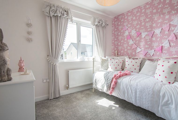 A bedroom with a daybed, pillows, curtains, and wallpaper.