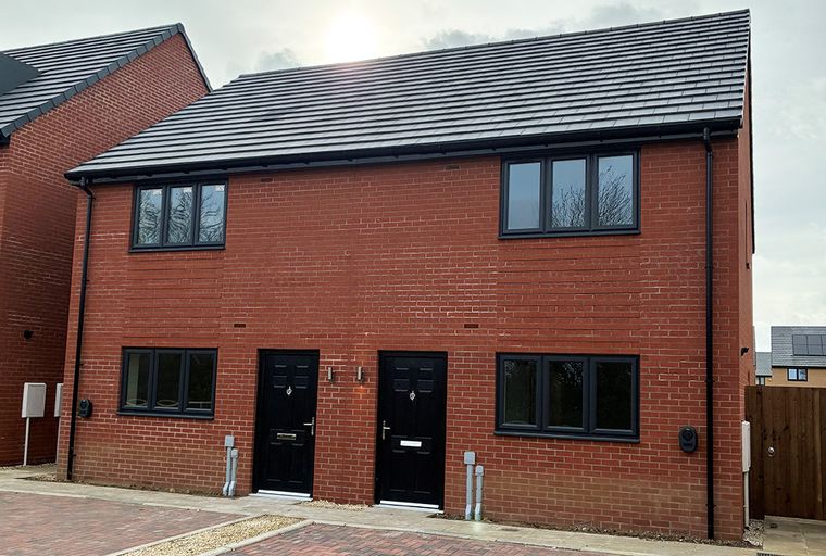 A pair of modern red brick houses with black doors and windows.