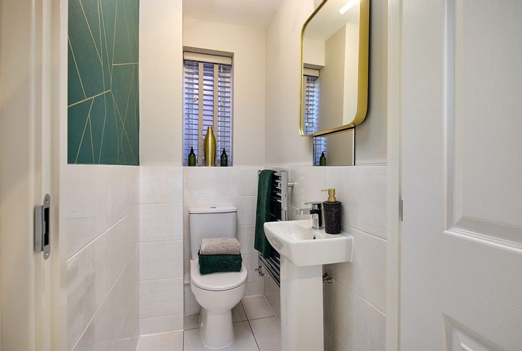 A bathroom with a toilet, sink, and mirror.