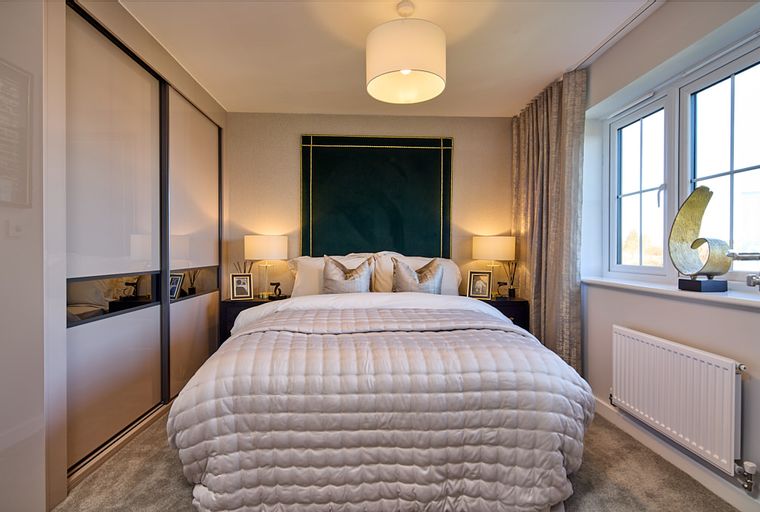 A bedroom with a bed, bedside tables, lamps, and a wardrobe.