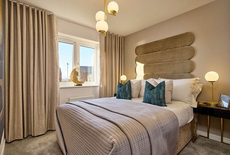 A bedroom with a bed, pillows, curtains, and a window.