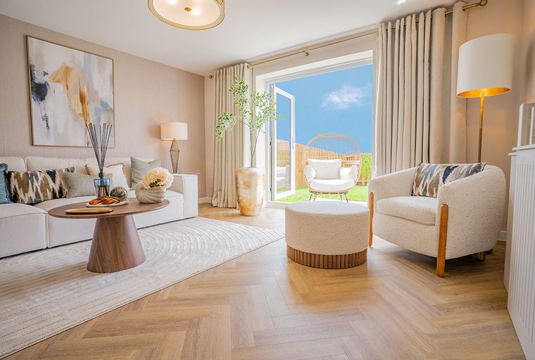 A living room with a sofa, coffee table, armchair, and double doors leading to a garden.