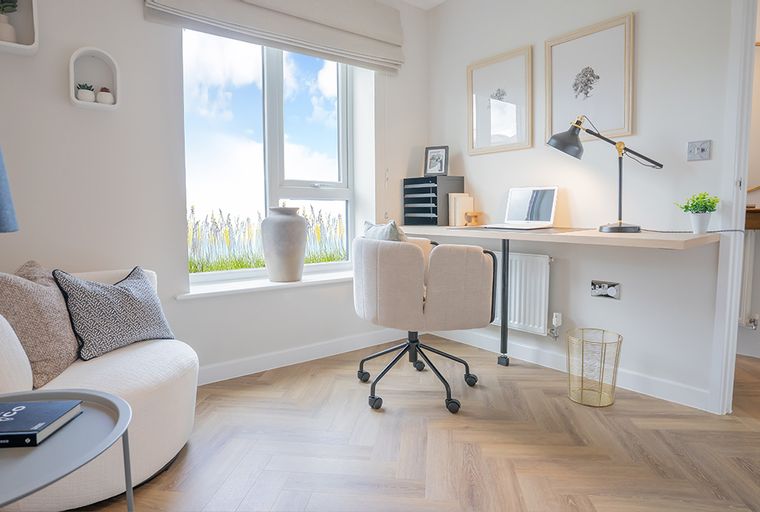 A home office with a desk, chair, and a large window.