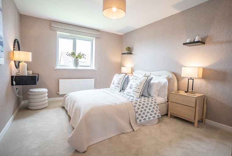 A bedroom with a bed, bedside tables, and a window.