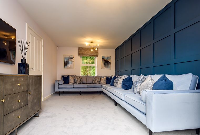 A living room with a sectional sofa, accent wall, and media console.