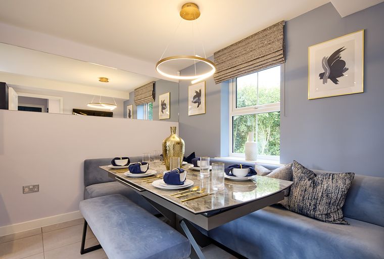 A dining area with a marble-top table, blue banquette seating, and a modern pendant light.