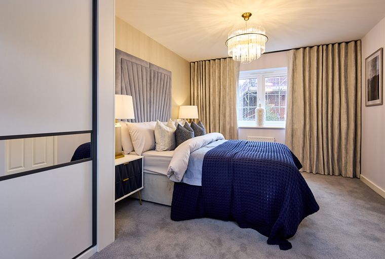 A bedroom with a bed, bedside tables, lamps, and a chandelier.