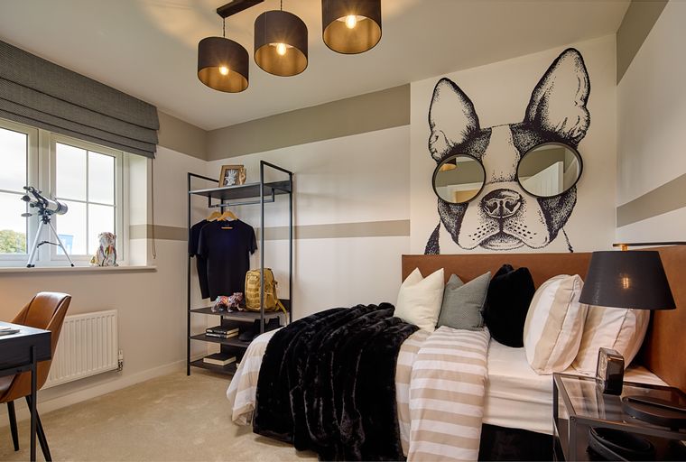 A bedroom with a bed, a clothing rack, and a desk.