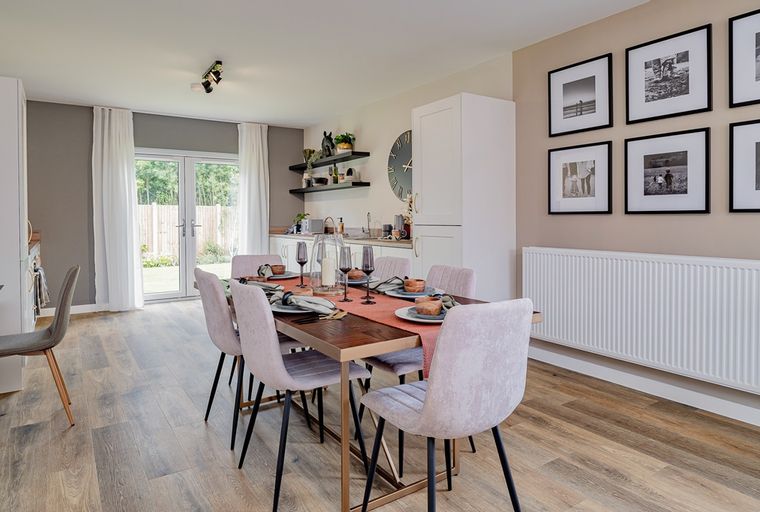 A dining room with a wooden table, chairs, and a kitchen area.