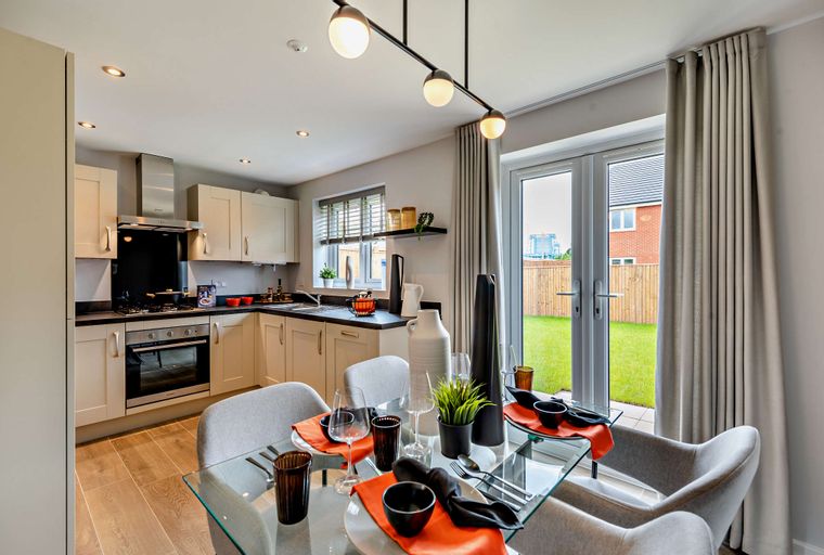 A dining area and kitchen with a glass-top table, chairs, and kitchen cabinets.