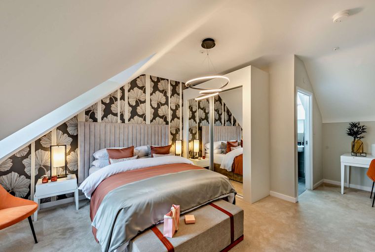 A bedroom with a bed, bedside tables, a mirrored wardrobe, and a desk.